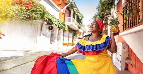 Eine fröhliche Frau in traditioneller kolumbianischer Tracht tanzt auf einer Straße in Cartagena