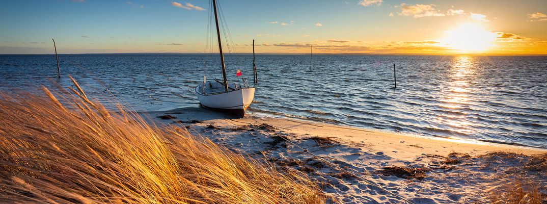 Ostseestrand auf der Insel Hel mit Dünengras, Meerblick und tief stehender Sonne