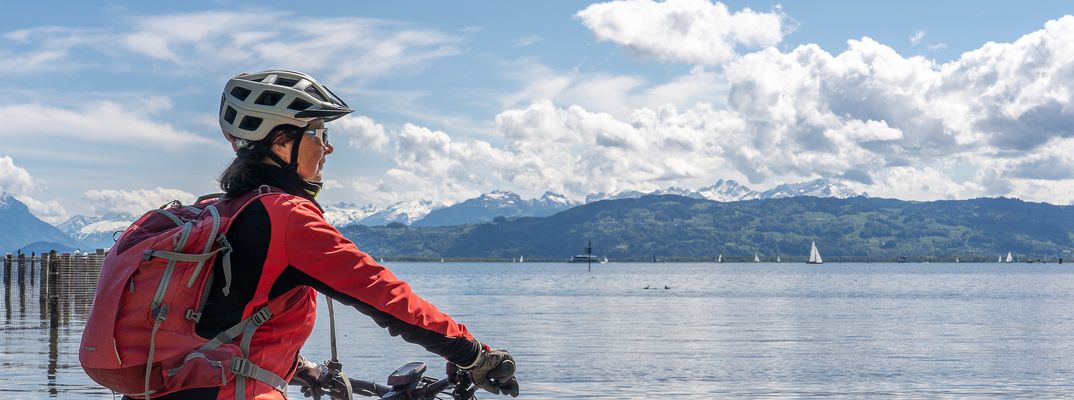 Frau auf einem Fahrrad blickt auf den Bodensee