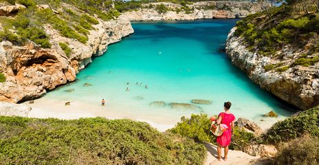 Frau blickt auf die Badebucht Calo des Moro mit türkisfarbenem Wasser und Felsen