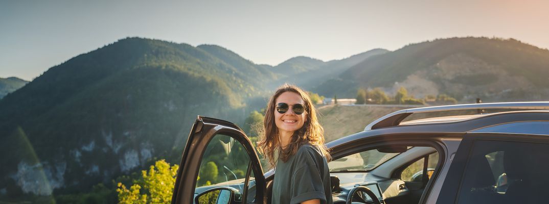 Frau steigt fröhlich aus ihrem Auto aus