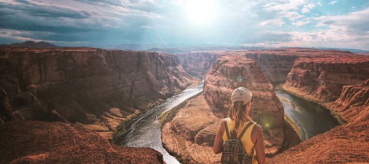 Frau in Rückansicht blickt auf die Schlucht des Grand Canyon in den USA