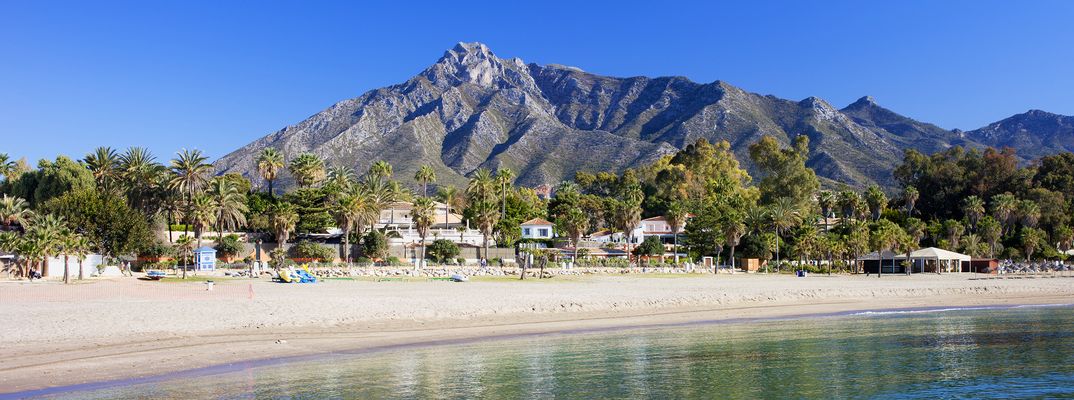 Der Berg La Concha erhebt sich hinter einem ruhigen Sandstrand und dem blauen Mittelmeer bei Marbella.