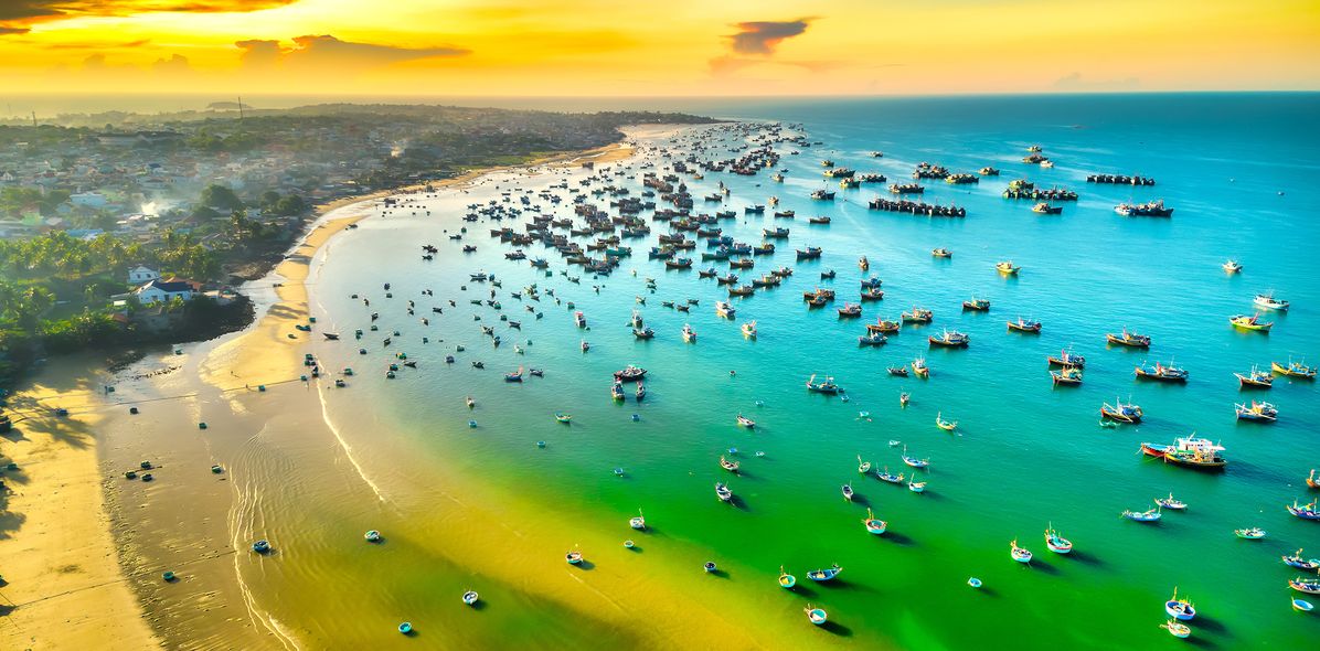 Luftansicht von der Küste Phan Thiets in Vietnam auf Strand und Meer mit vielen Booten bei gedämpften Licht