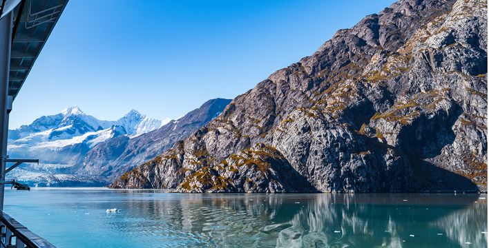 Blick vom Kreuzfahrtschiff auf die felsige Berglandschaft und schneebedeckten Gipfel der Glacier Bay in Alaska
