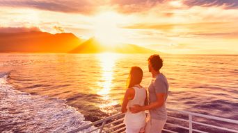 Paar auf Kreuzfahrtschiff bei Sonnenuntergang