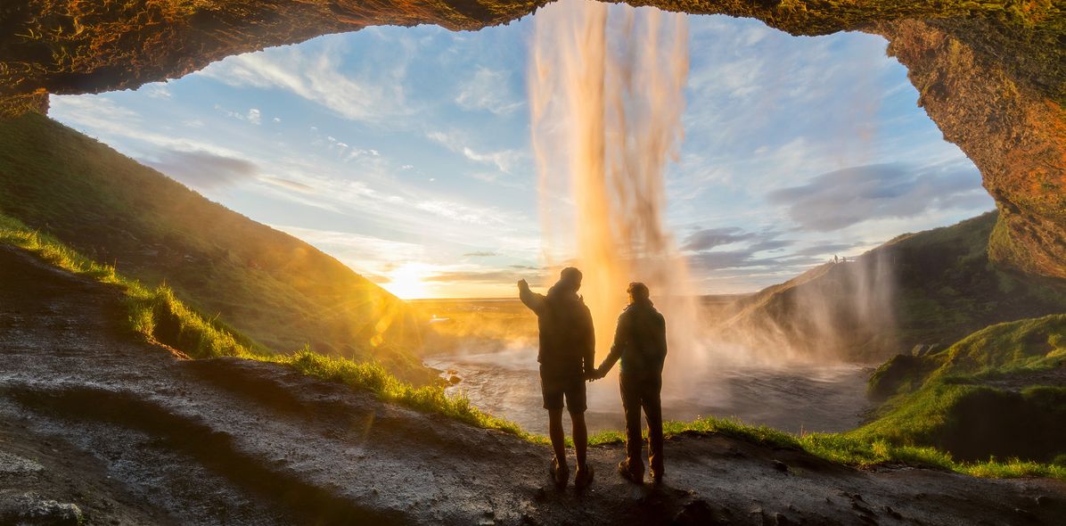 Paar bei Sonnenaufgang am Seljalandsfoss-Wasserfall auf Island