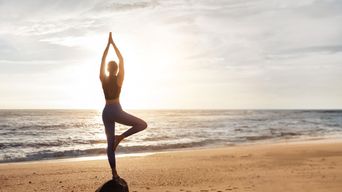 Frau macht Yoga am Strand