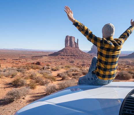 Reisender neben einem Mietwagen mit Blick auf das Monument Valley in den USA