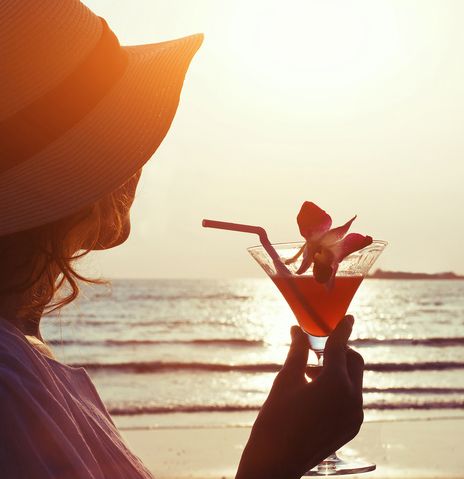 Frau mit Cocktail am Strand