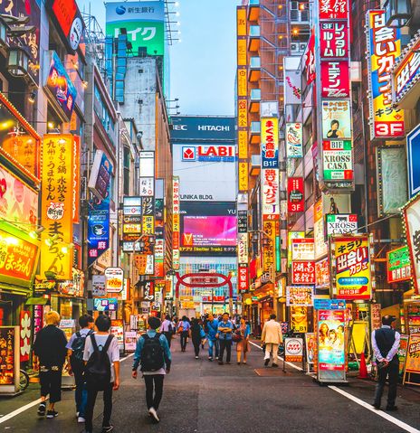 Straße in Tokio mit bunten Schildern und Menschen