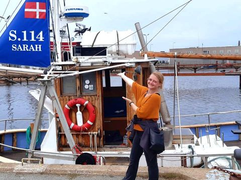 Berge & Meer-Mitarbeiterin Sarah vor einem Segelboot in Skagen