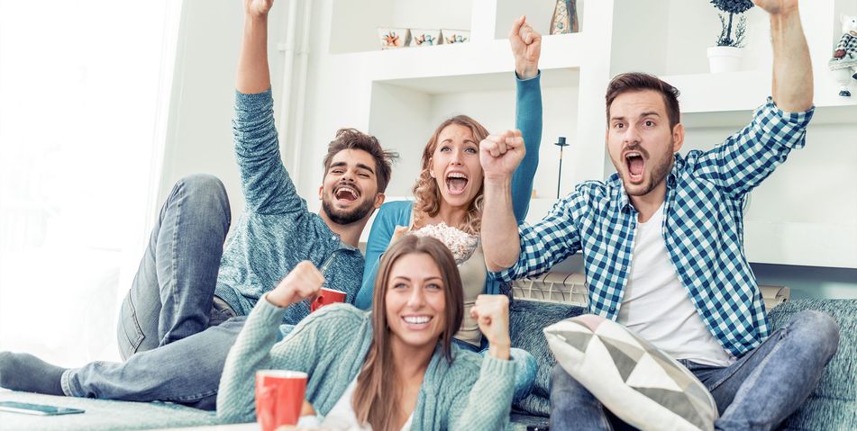 Gruppe von Freunden im Wohnzimmer jubelt