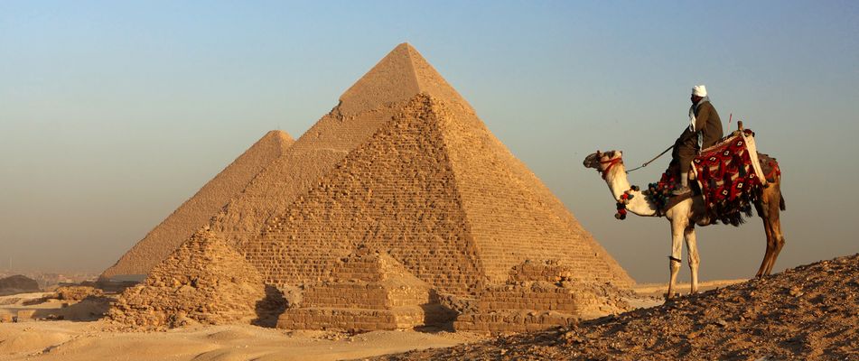 Beduine auf einem Kamel in der Wüste im Hintergrund Pyramide