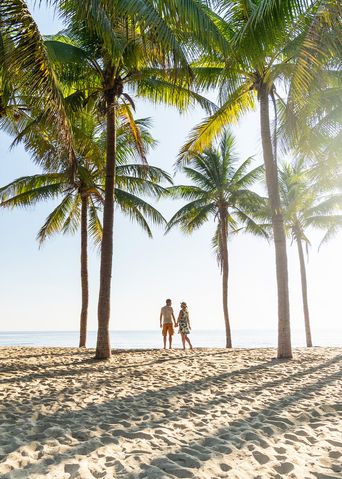 Paar gemeinsam am Strand unter Palmen