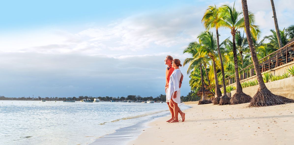 Ein Paar steht am Strand und schaut auf das Meer