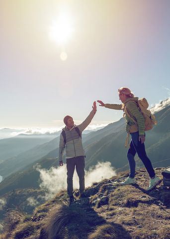 Paar breitet die Arme auf einem Berggipfel mit weitem Panorama aus