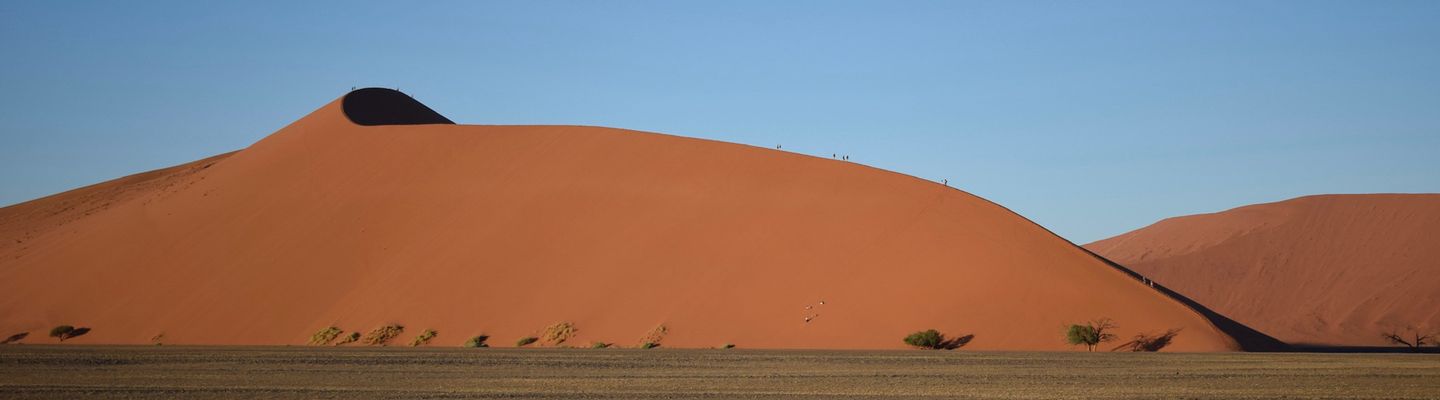 Rote Sanddünen der Namib-Wüste in Namibia unter blauem Himmel