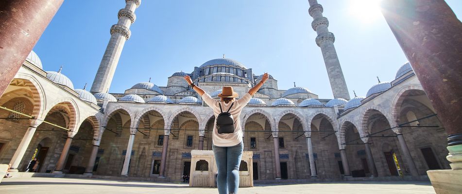 Frau steht im Innenhof einer Moschee in Istanbul mit Blick auf Kuppeln