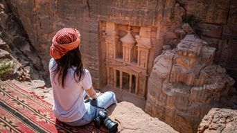 Frau blickt von Felsen auf das Schatzhaus in Petra
