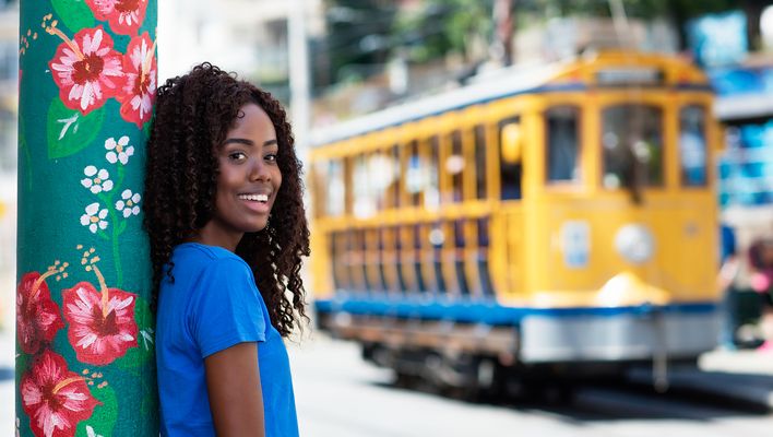 Lächelnde Frau vor ikonischer gelber Straßenbahn in Rio de Janeiro, Brasilien