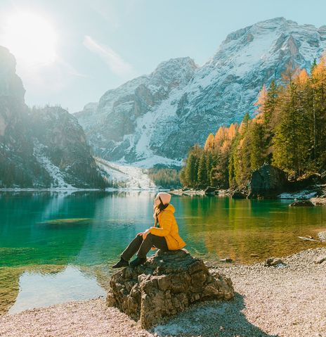 Frau sitzt auf Stein am See