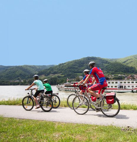 Fahrradfahrer mit Flusskreuzfahrtschiff