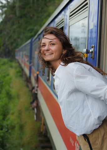 Frau lehnt sich bei der Fahrt aus einem Zug in Sri Lanka