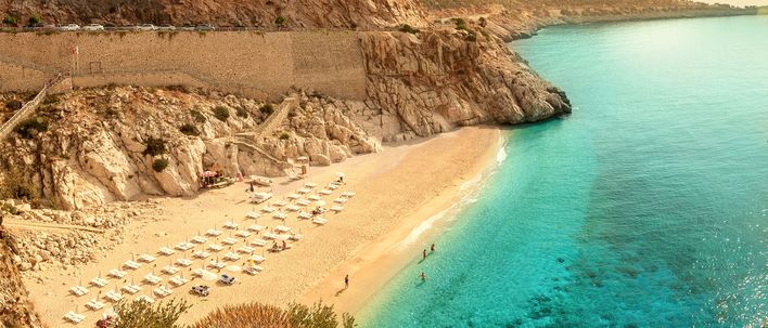Die helle Sandbucht KAPUTAŞ BEACH an der türkischen Riviera mit klarem Wasser und felsiger Küstenlandschaft