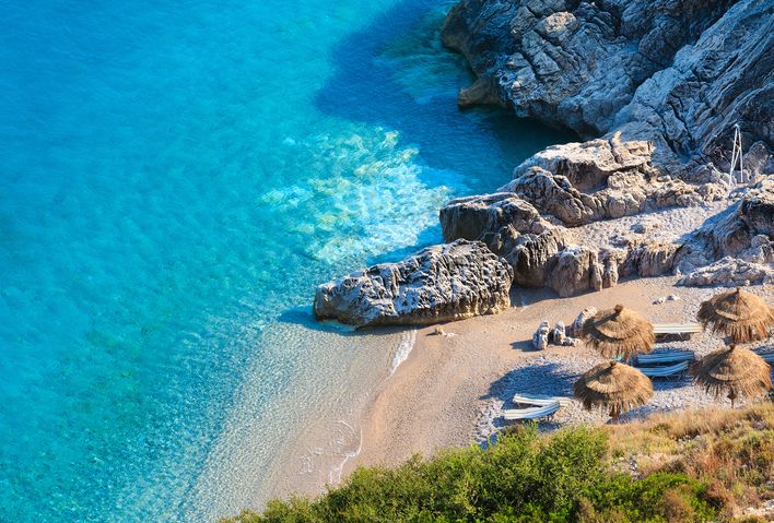  Der malerische Strand von Himare an der albanischen Riviera mit türkisfarbenem Wasser und Sonnenschirmen