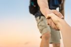 Wanderer reicht die Hand, um den Aufstieg zu erleichtern