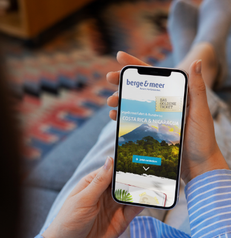 Frau hält ihr Handy in den Händen und liest den Berge & Meer Newsletter
