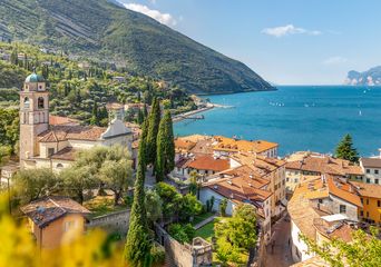 Blick auf Torbole am Gardasee mit Altstadt, Kirche, grünen Hügeln und Gardasee im Hintergrund