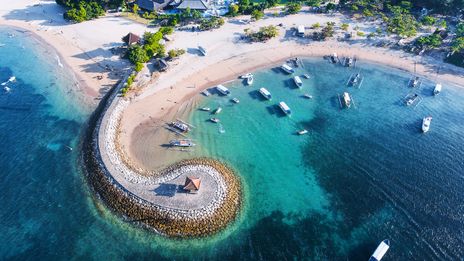 Luftaufnahme der geschwungenen Bucht von Nusa Dua mit Booten