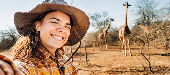 Frau macht ein Selfie mit Giraffen bei einer Safari in Südafrika