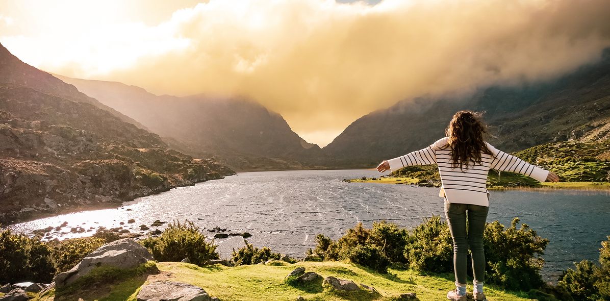 Frau auf Felsen schaut auf See in Irland