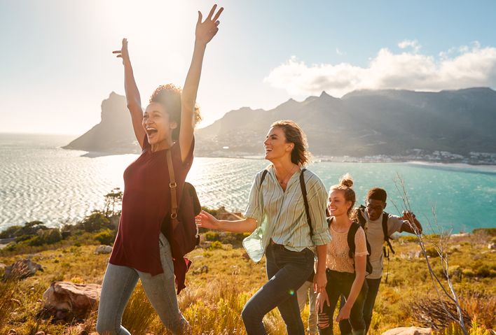 Fröhliche Gruppe beim Wandern mit Ausblick auf das Meer