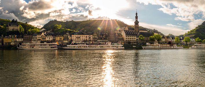 Panoramablick auf Cochem an der Mosel mit Reichsburg, historischen Häusern und Flusskreuzfahrtschiffen im Sonnenlicht