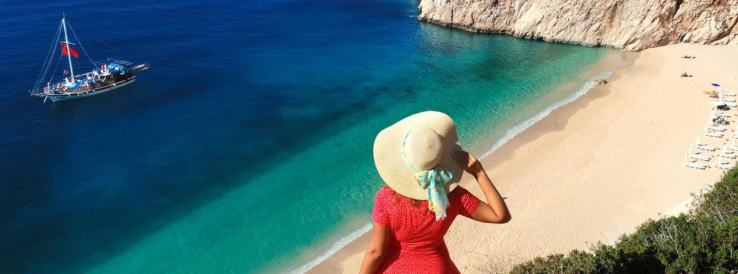 Frau mit Sonnenhut blickt auf eine Bucht an der türkischen Küste
