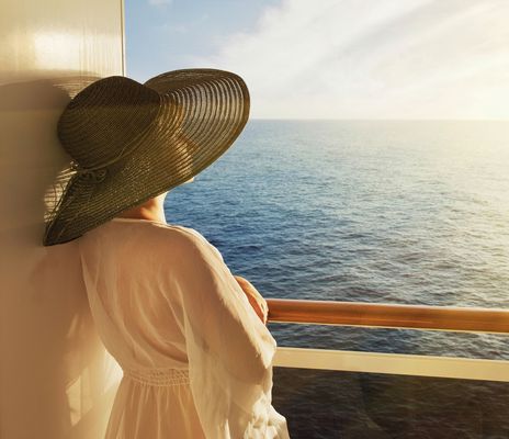 Frau steht auf dem Balkon und schaut auf das Meer