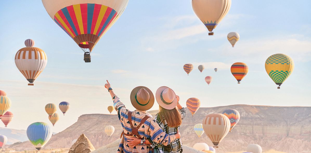 Paar blickt auf Heißluftballons in Kappadokien