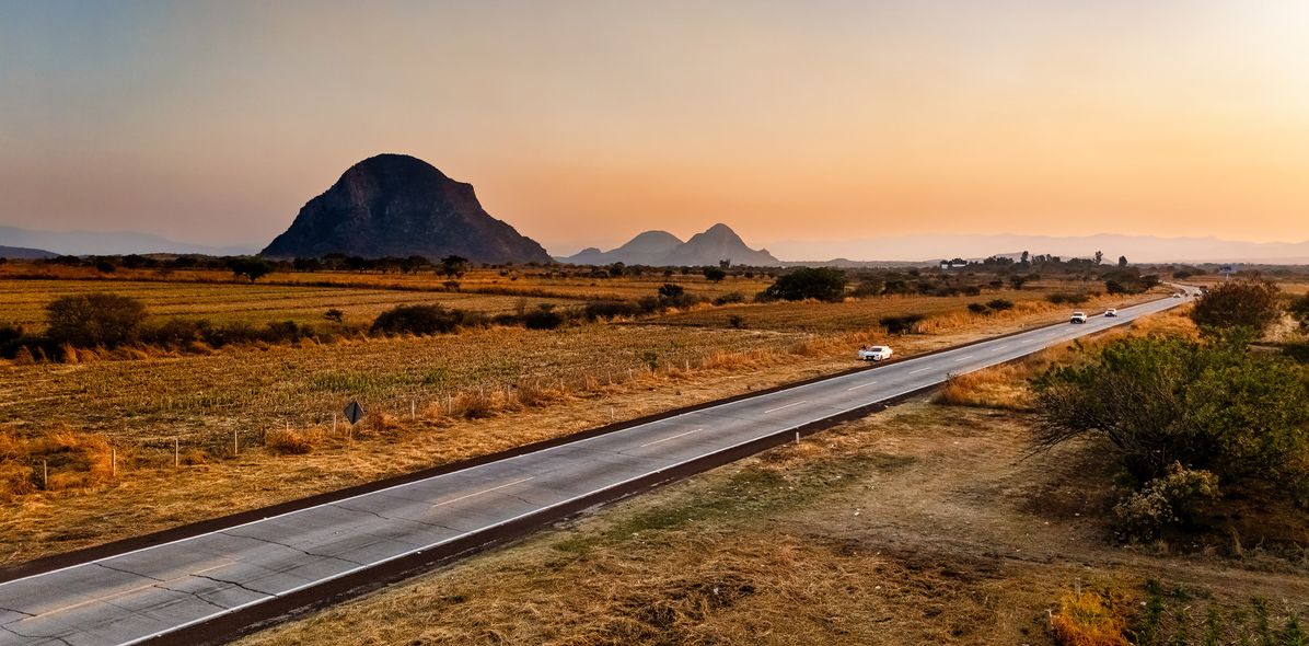Landstraße durch die weite Landschaft Mexikos bei Sonnenuntergang