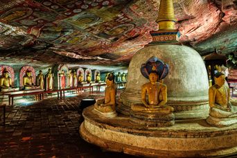Innenansicht des Dambulla-Höhlentempels mit goldenen Buddha-Statuen und farbenprächtigen Wandmalereien