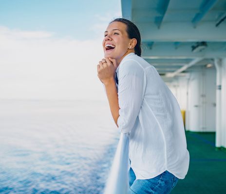 Frau an der Reling eines Kreuzfahrtschiffes