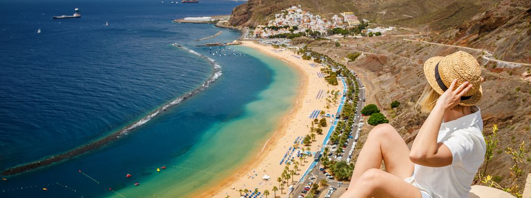 Frau blickt auf den goldgelben Sandstrand Playa de las Teresitas mit türkisblauem Meer auf Teneriffa