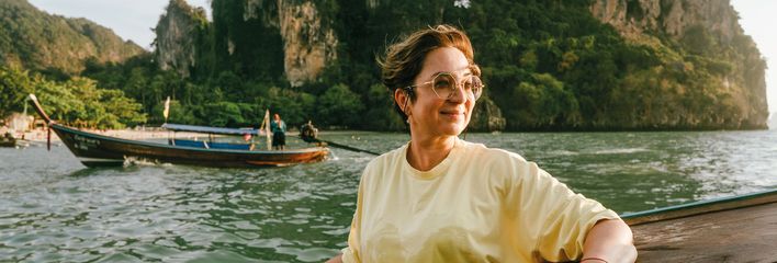 Frau genießt eine Bootsfahrt vor den Kalksteinfelsen der thailändischen Inselwelt bei Krabi