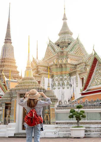 Frau mit Hut und Rucksack blickt auf den Wat Pho Tempel in Bangkok