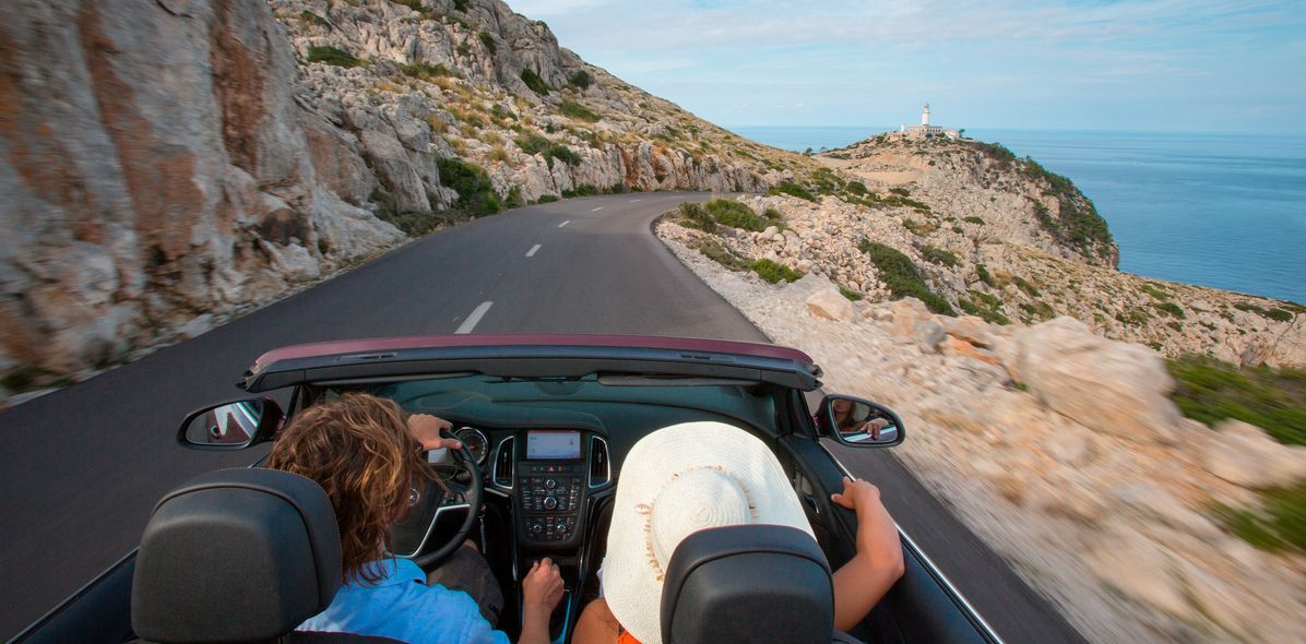 Paar im Auto auf einer Küstenstraße in Italien