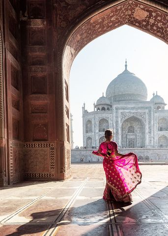 Frau in traditioneller indischer Kleidung vor einem Torbogen zum Taj Mahal in Indien