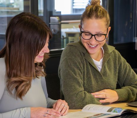 Mitarbeiterinnen Janina und Julia schauen sich etwas gemeinsam an